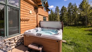Een houten chalet met een hottub ervoor.