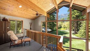 Una habitación amplia con un gran ventanal que ofrece vistas a un jardín exuberante y montañas.