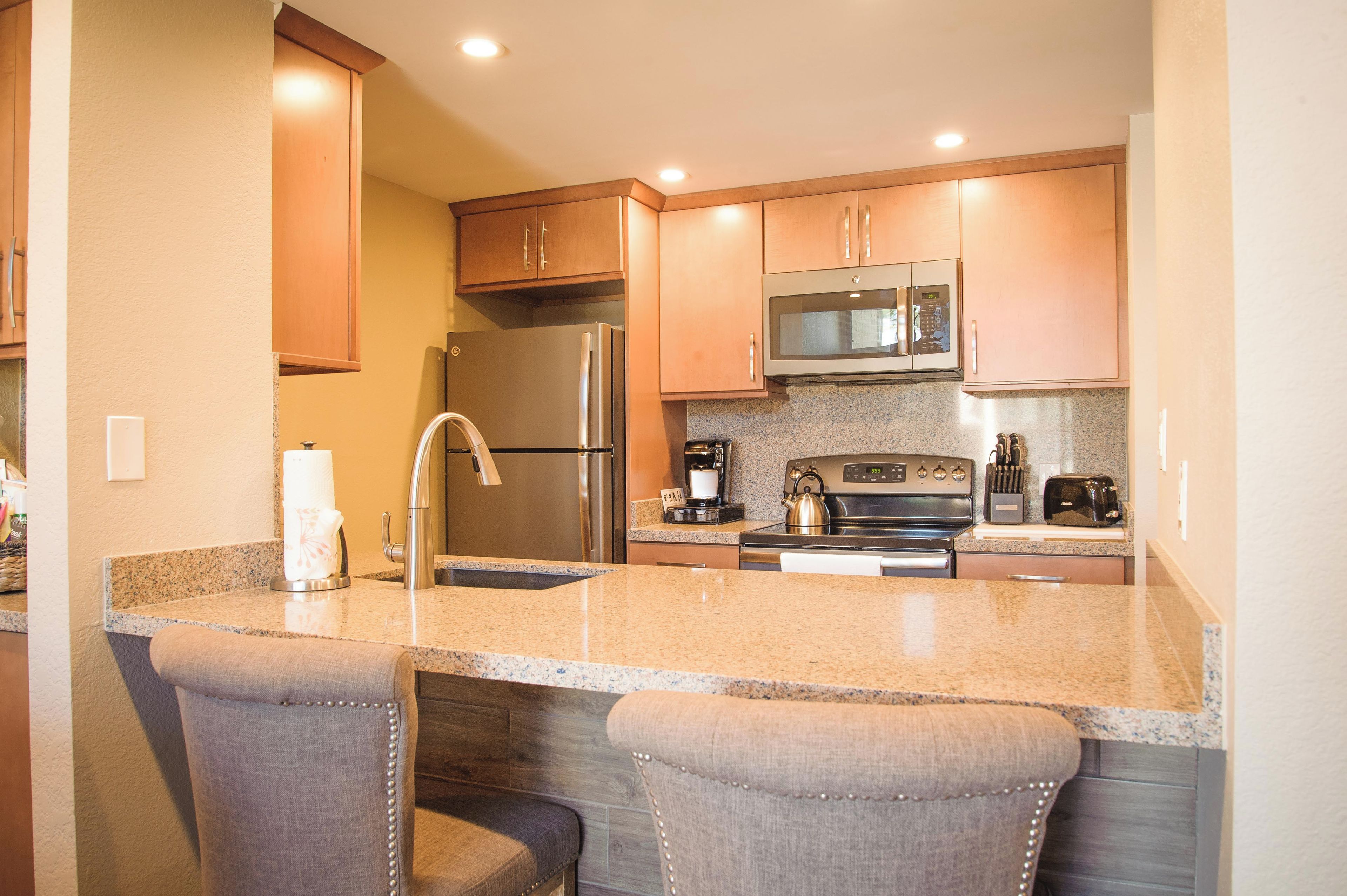 A modern kitchen with granite countertops, stainless steel appliances, and wooden cabinets.