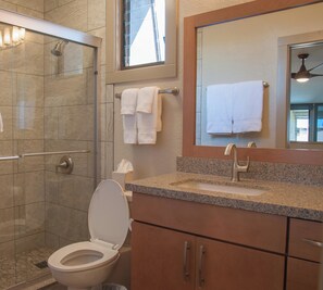 A bathroom with a shower, toilet, sink, and a mirror with a towel rack.