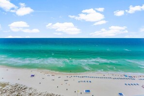 A beach with clear turquoise waters, a sandy shore, and a few beach umbrellas.