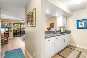Una cocina moderna con armarios blancos, encimera de granito y pileta integrada.