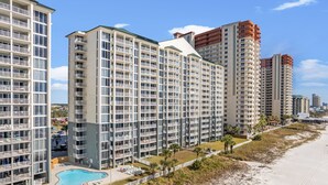 Un hotel moderno de gran altura con varios balcones, piscina y vista al mar.