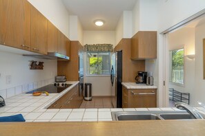 A compact kitchen with wooden cabinets, a stainless steel refrigerator, a toaster, and a coffee maker.