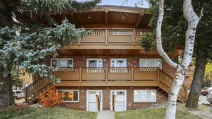 Ein mehrstöckiges Gebäude mit einem Holzbalkon, einer Ziegel-Fassade und einem zentralen Eingang.