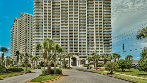 A large, multi-story hotel with a central entrance, surrounded by palm trees and well-maintained lawns. - After Dune Delight ~ 2BR/2BA ~ 15th Floor ~ (Miramar Beach)