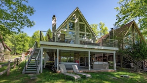 Una casa de dos pisos con balcón, escaleras y mobiliario exterior.