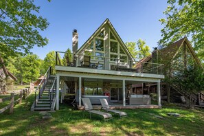 A two-story house with a balcony, a staircase, and outdoor seating.