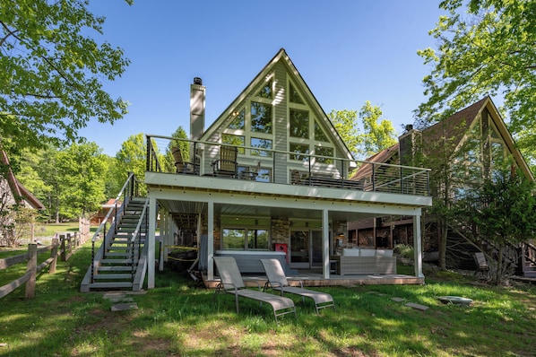 A two-story house with a balcony, a staircase, and outdoor seating.