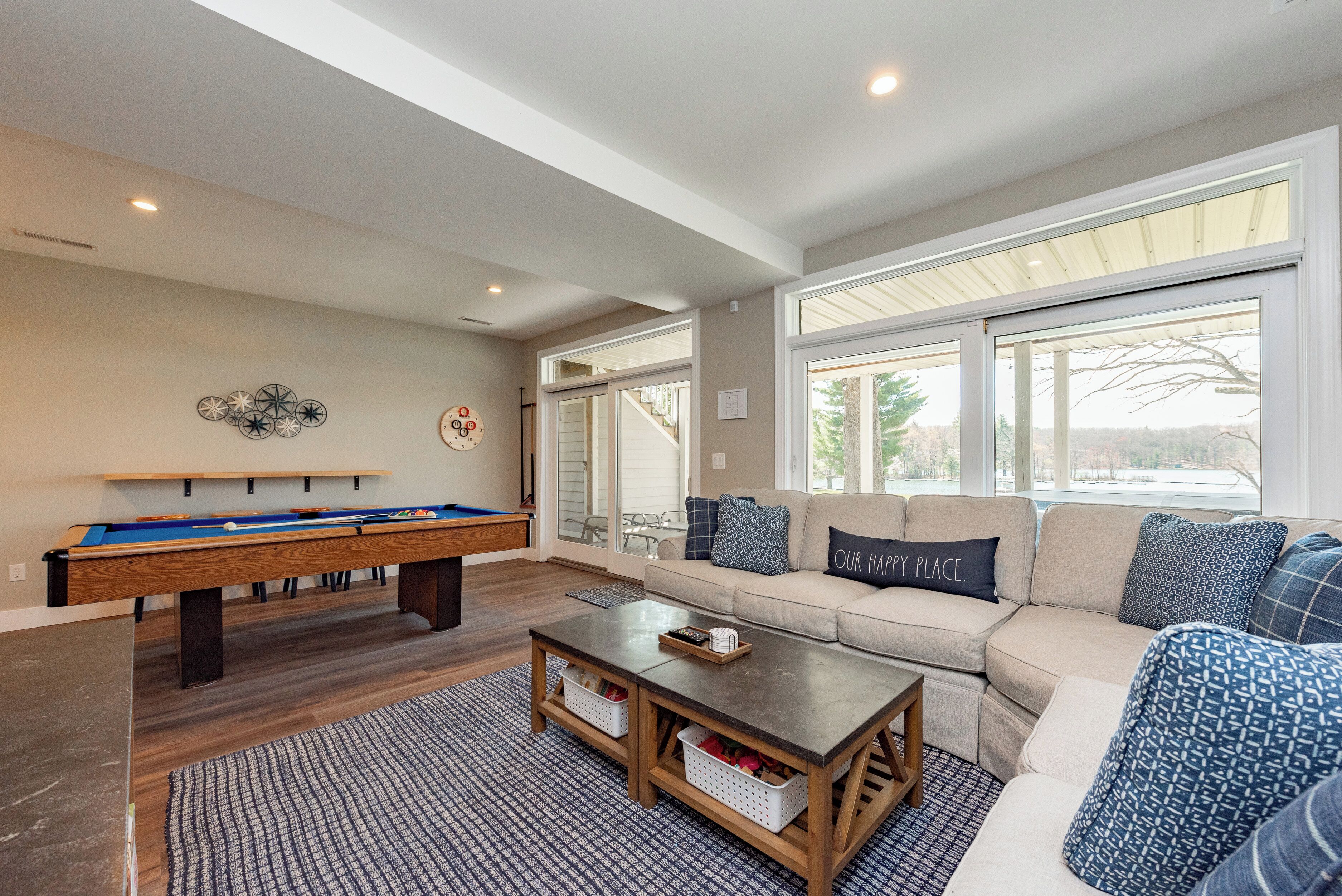 A cozy living room with a pool table, a sofa with patterned cushions, and a coffee table.
