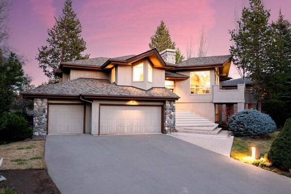 A modern two-story house with a stone facade, a garage, and a well-maintained driveway. - 3 Mulligan - Hot Tub with Wooded Views, Wine Cellar, SHARC passes, Comfort & Style (Sunriver)