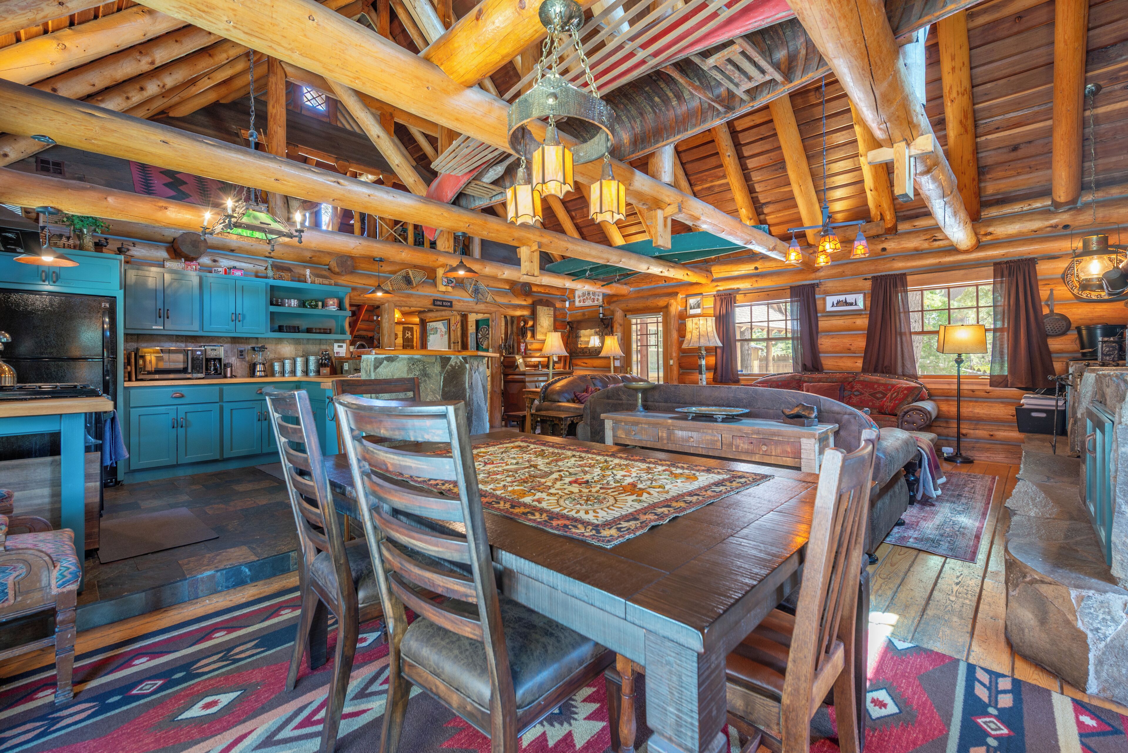 L’intérieur d’un chalet rustique comprend une table à manger en bois, des chaises, un canapé et un coin cuisine.