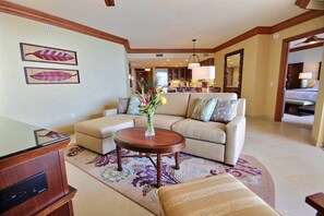 Una sala de estar con un sofá, una mesa de centro y un mueble para la televisión. Hay un jarrón con flores sobre la mesa de centro.