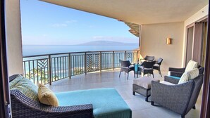 Un balcón con muebles de mimbre, una mesa y sillas, con vista a una playa y al océano.