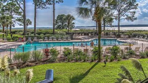 A pool area with multiple swimming pools, surrounded by palm trees and lounge chairs. - 1865 Beachside Tennis- Easy Access to Beach & Pool. (Hilton Head Island)