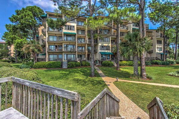 A multi-story hotel with balconies, a well-maintained lawn, and a wooden deck.