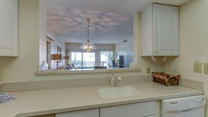 A kitchen with a large window, a dishwasher, and a mirror above the sink. - 1865 Beachside Tennis- Easy Access to Beach & Pool. (Hilton Head Island)