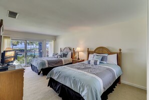 Ein Hotelzimmer mit zwei Betten, einem Fernseher und einem Balkon mit Blick.