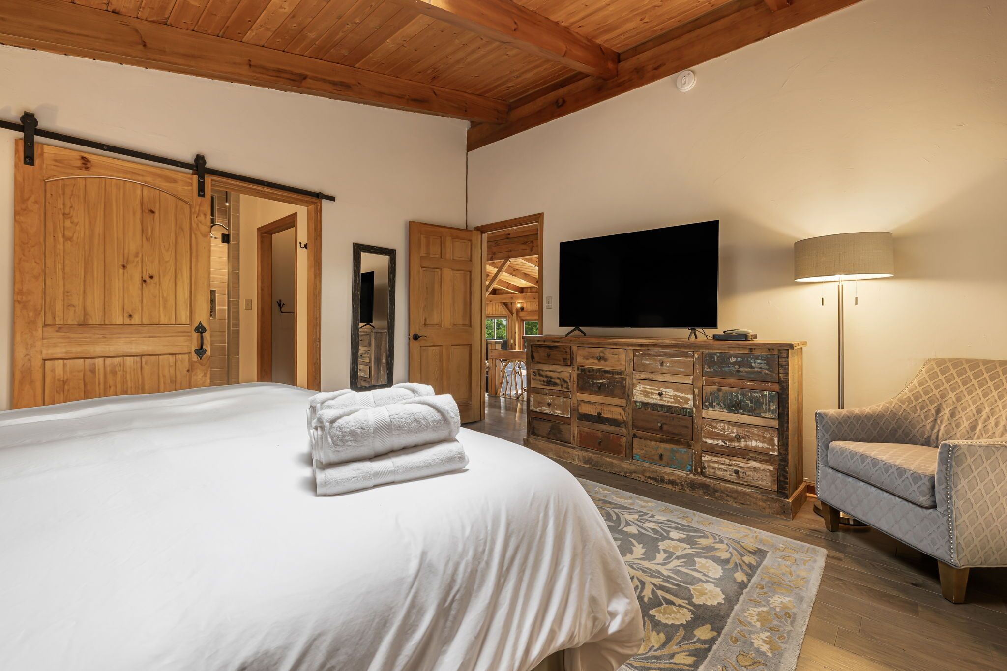 Un dormitorio con una cama grande, un armario de madera, televisión y una lámpara.