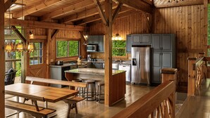 Una cabaña rústica de madera con cocina, comedor y bar.