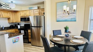 Une cuisine moderne avec des meubles en bois, des appareils en acier inoxydable et un coin repas comprenant une table ronde et des chaises.