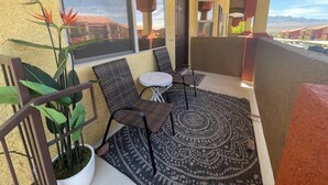 Un balcon avec un espace salon, un pot de fleurs et une vue sur le paysage urbain.