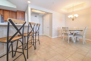 A kitchen with a dining area, featuring a kitchen island, bar stools, and a dining table with chairs.