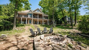 Ein großes Haus mit Natursteinfassade, mehreren Balkonen und einer Feuerstelle mit Adirondack-Stühlen.