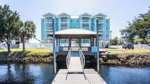 A waterfront hotel with a dock leading to a covered area, surrounded by a white fence and palm trees. - Remodeled! Waterfront, Rivers Edge Condo #1C-Bldg 1 *DOCK w/ASSIGNED BOAT SLIP! (Steinhatchee)