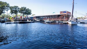 A marina with boats docked, a building with a covered area, and a clear sky. - Remodeled! Waterfront, Rivers Edge Condo #1C-Bldg 1 *DOCK w/ASSIGNED BOAT SLIP! (Steinhatchee)