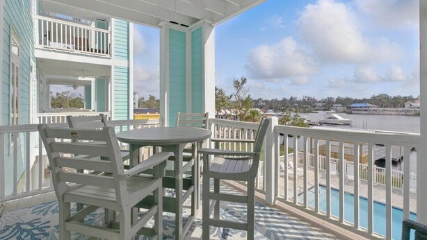 A covered outdoor area with a pool, white and turquoise furniture, and a view of a marina. - Remodeled! Waterfront, Rivers Edge Condo #1C-Bldg 1 *DOCK w/ASSIGNED BOAT SLIP! (Steinhatchee)