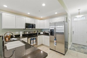 Modern kitchen with a refrigerator, microwave, oven, and sink.