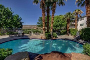 A swimming pool with lounge chairs and palm trees.