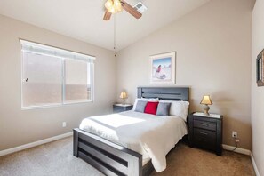 A bedroom with a bed, nightstands, a ceiling fan, a window, and a framed picture on the wall.