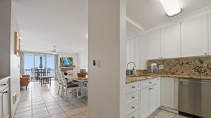 A modern kitchen with white cabinets, a granite countertop, and a dishwasher. - Absolute Beach Front Cottage! Panoramic Views E20 North Coast Village (Oceanside)