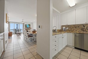 A modern kitchen with white cabinets, a granite countertop, and a dishwasher.