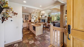 A spacious kitchen with a central island, wooden cabinetry, and a stone fireplace.