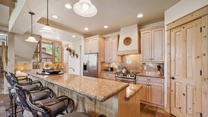 A spacious kitchen with a large island, wooden cabinets, and a stainless steel refrigerator.