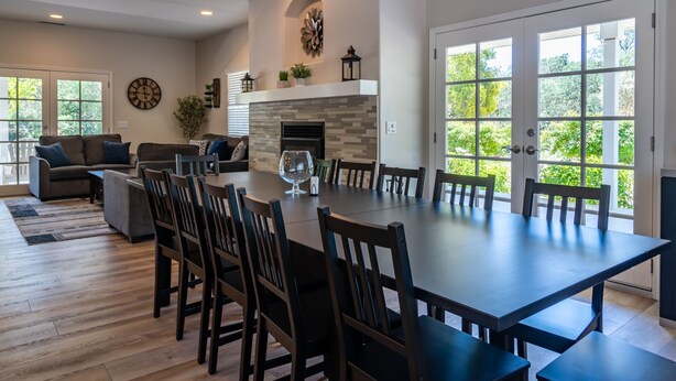 A spacious dining area with a large table and chairs, a fireplace, and a view through large windows.