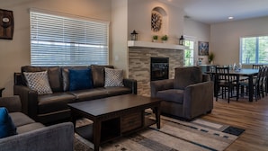 A modern living room with a sofa, armchairs, a coffee table, and a fireplace.