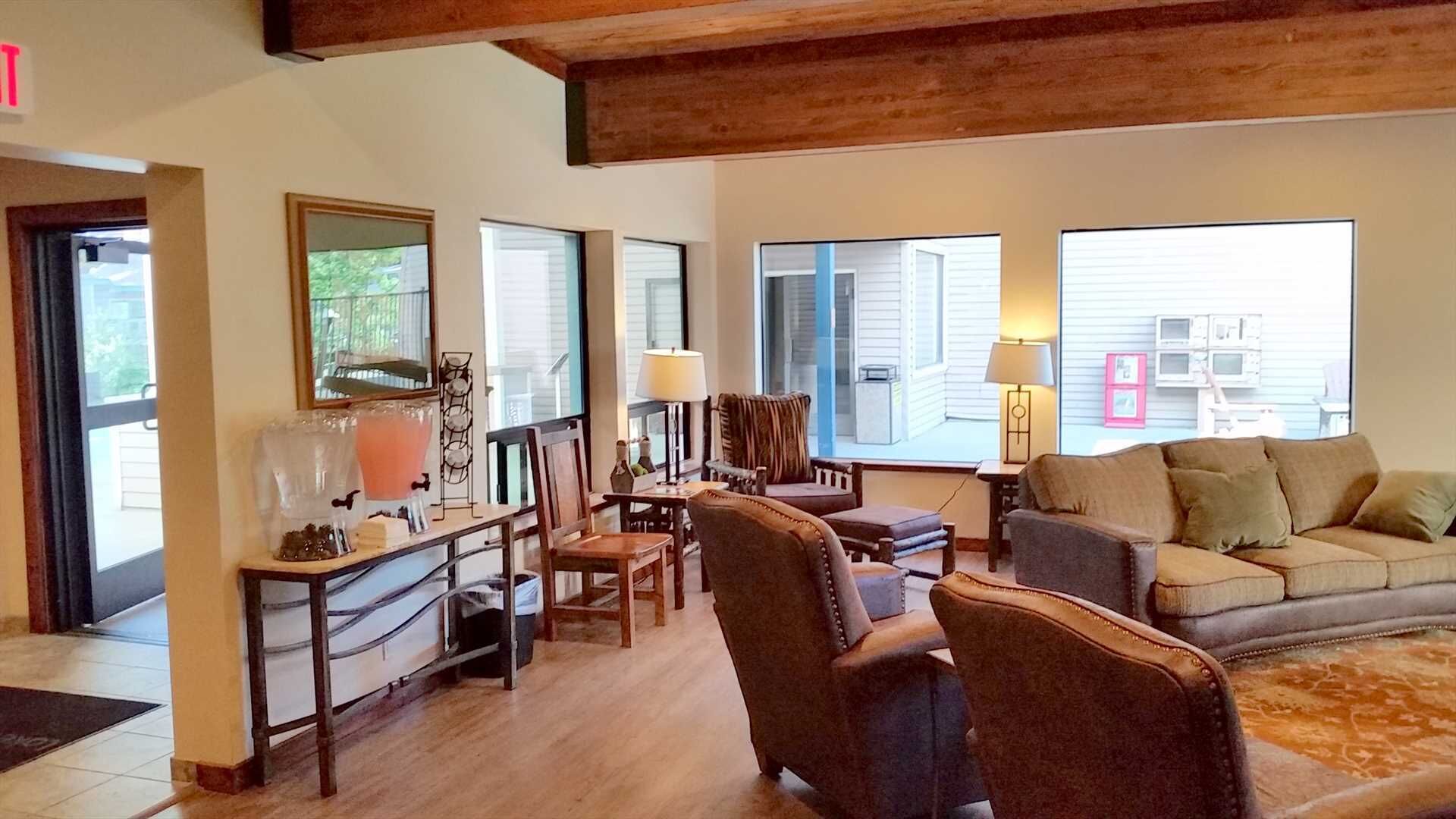 A spacious living room with a wooden ceiling, a sofa, armchairs, a coffee table, and a dining area with a table and chairs.