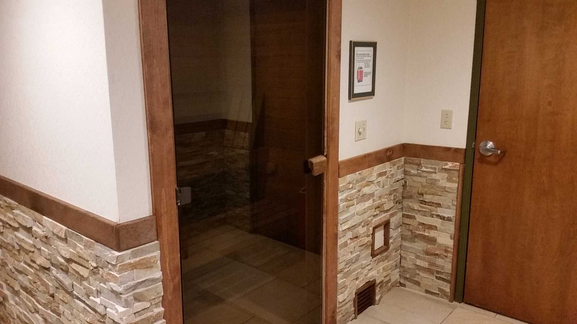 Un pasillo estrecho con una puerta de madera que da a un baño con paredes de piedra y piso de baldosas.