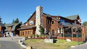A rustic lodge with a stone chimney, wooden exterior, and outdoor seating area.