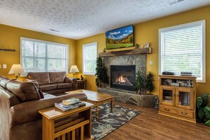 A living room with a fireplace, leather sofa, and a television mounted on the wall.