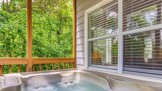 Un jacuzzi en una terraza de madera con vistas a exuberante follaje.