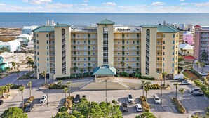 Ein mehrstöckiges Hotel mit Innenhof, Parkplatz und Blick auf das Meer.