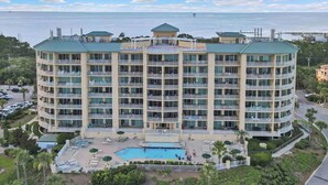 Ein mehrstöckiges Hotel mit Balkonen, einem Swimmingpool und Meerblick.