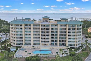 A multi-story hotel with balconies, a swimming pool, and a view of the ocean.