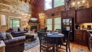 A log cabin interior with a living room, dining area, and kitchen.