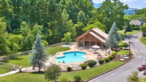 A lodge with a swimming pool, outdoor seating, and a mountain backdrop.